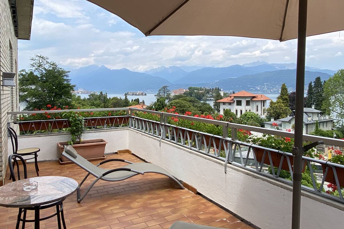 Un balcone con vista sulle montagne e su un lago. Sul balcone si trova un tavolo e una sedia.