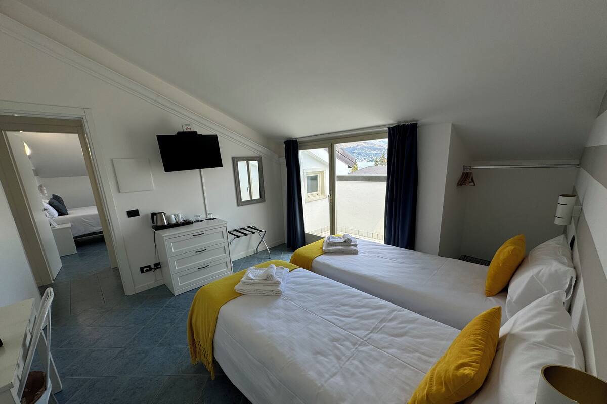 Una camera d'albergo con due letti, una TV, una scrivania con sedia e una finestra vista panoramica.