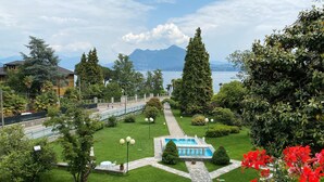 Un jardín ajardinado con piscina, un sendero y vistas a un lago y montañas.