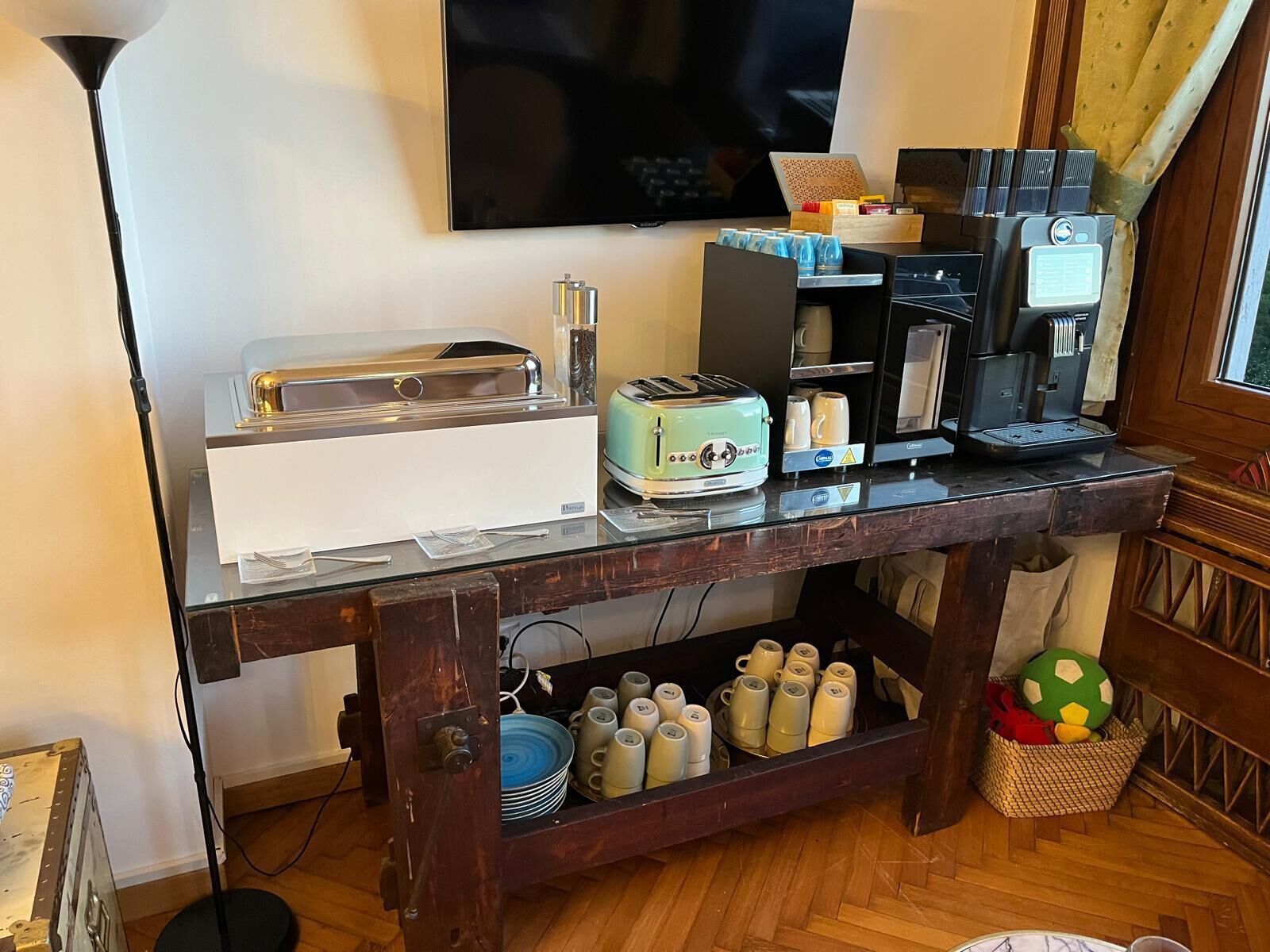Una kitchenette con tostadora, cafetera y televisor montado en la pared.