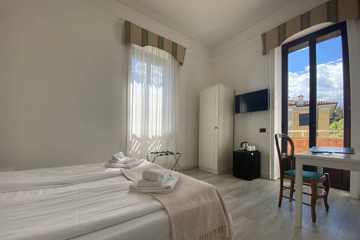 Camera d'albergo con un letto, una scrivania con una sedia, una televisione e vista sull'esterno.