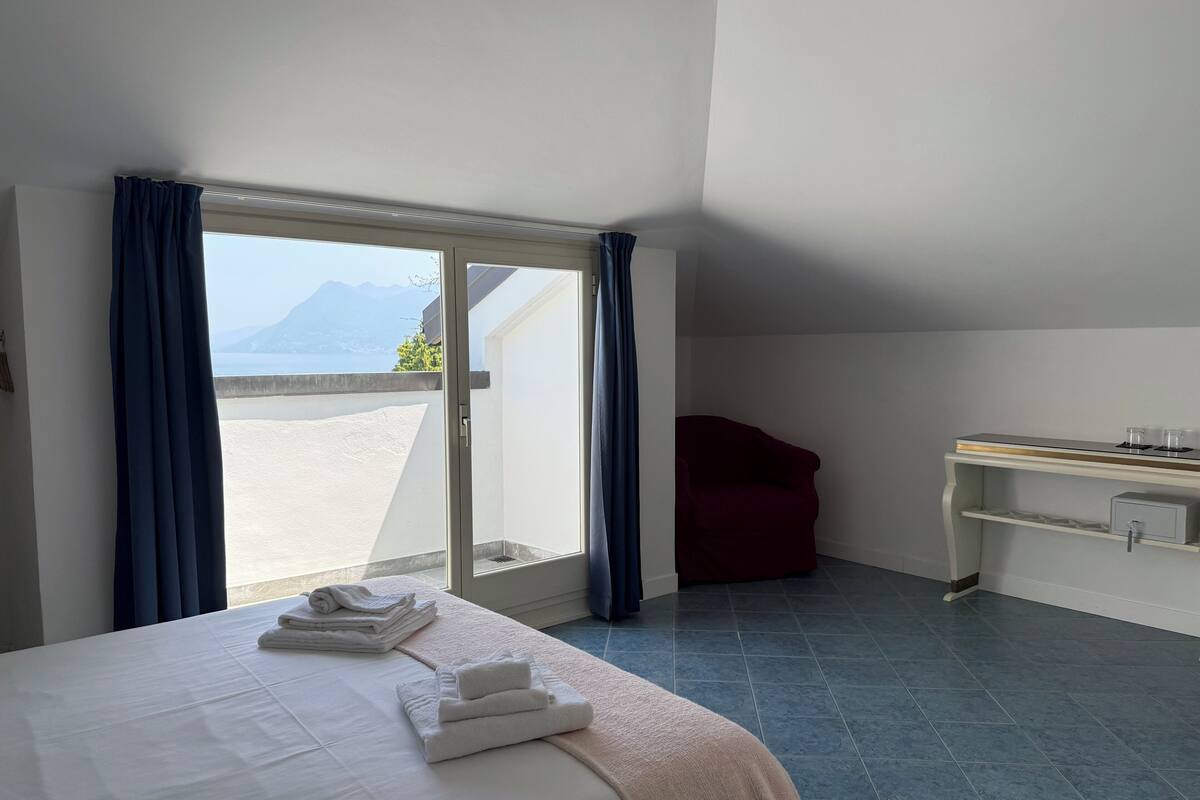 Una camera d'albergo con un letto, una scrivania e vista sul mare.