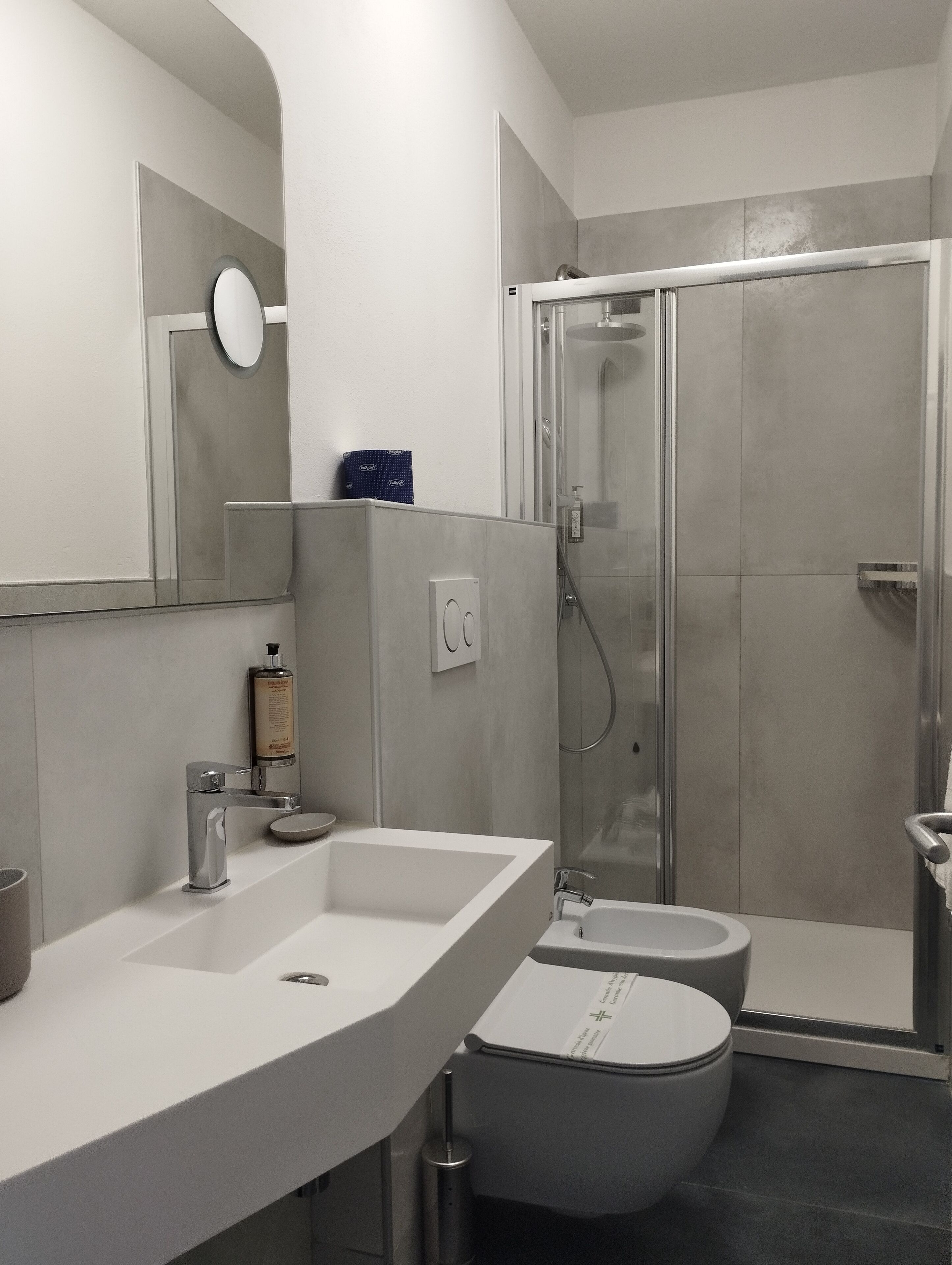 Un baño moderno con ducha, inodoro y dos lavamanos.