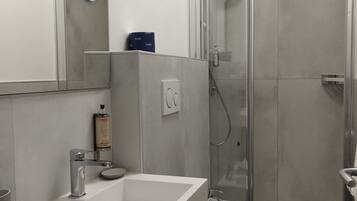 Un baño moderno con ducha, inodoro y dos lavamanos.