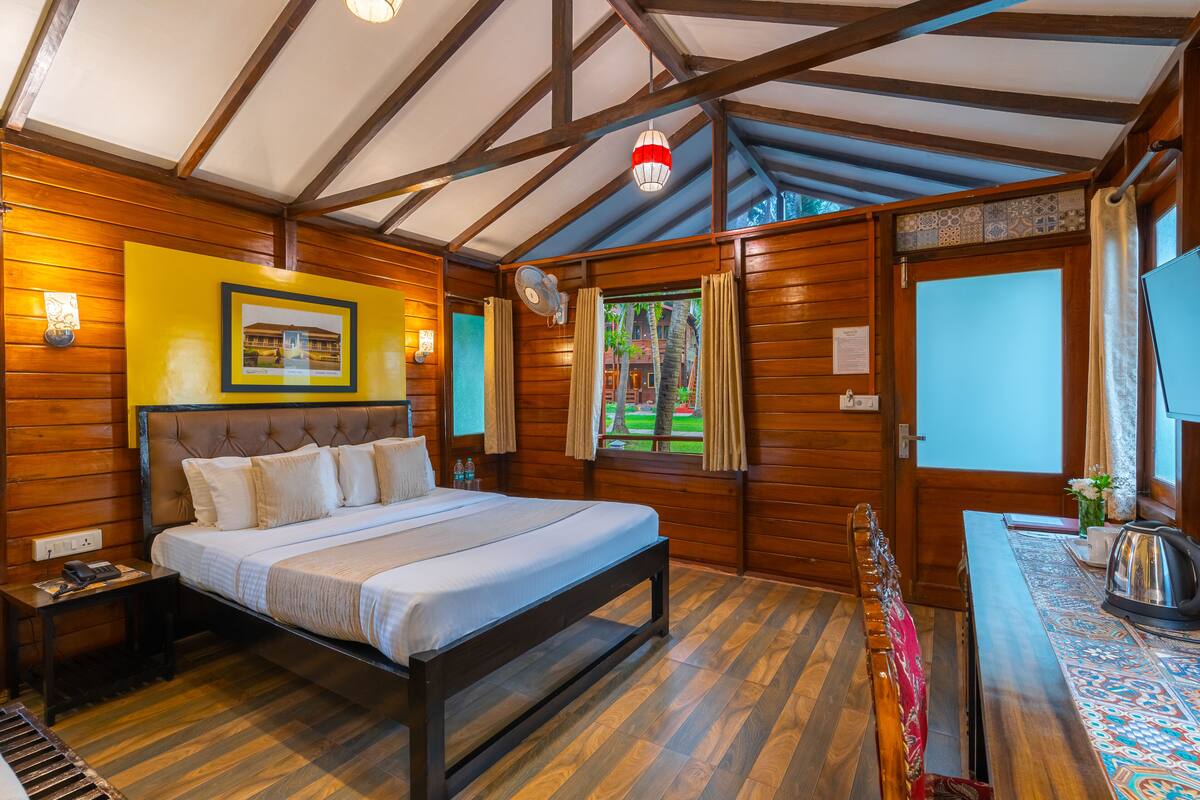 A wooden cabin-style room with a bed, bedside table, and a window with curtains.