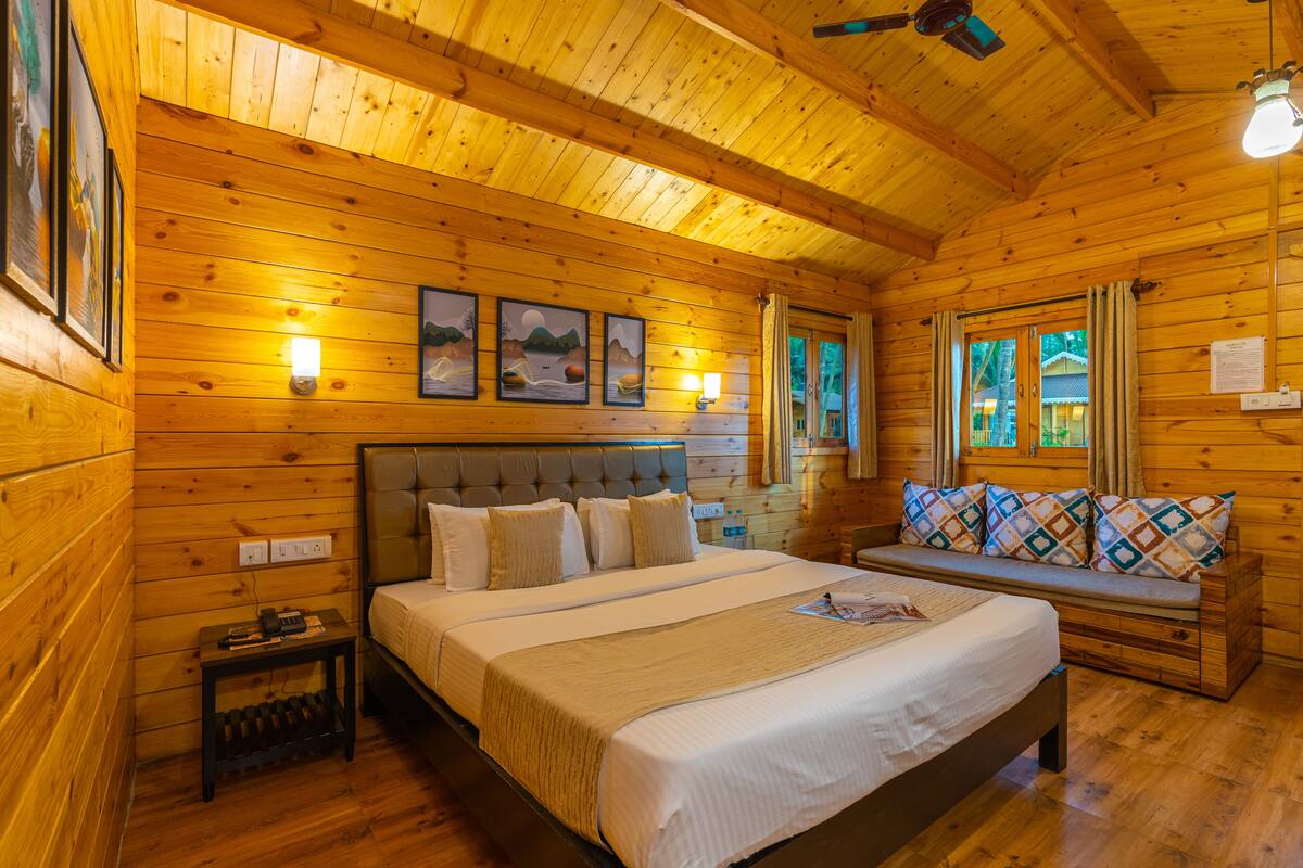 A wooden cabin room with a large bed, a bench, and a small table.