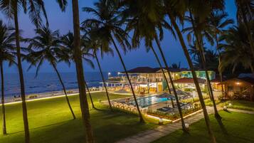 A resort with a pool, palm trees, and a view of the ocean.