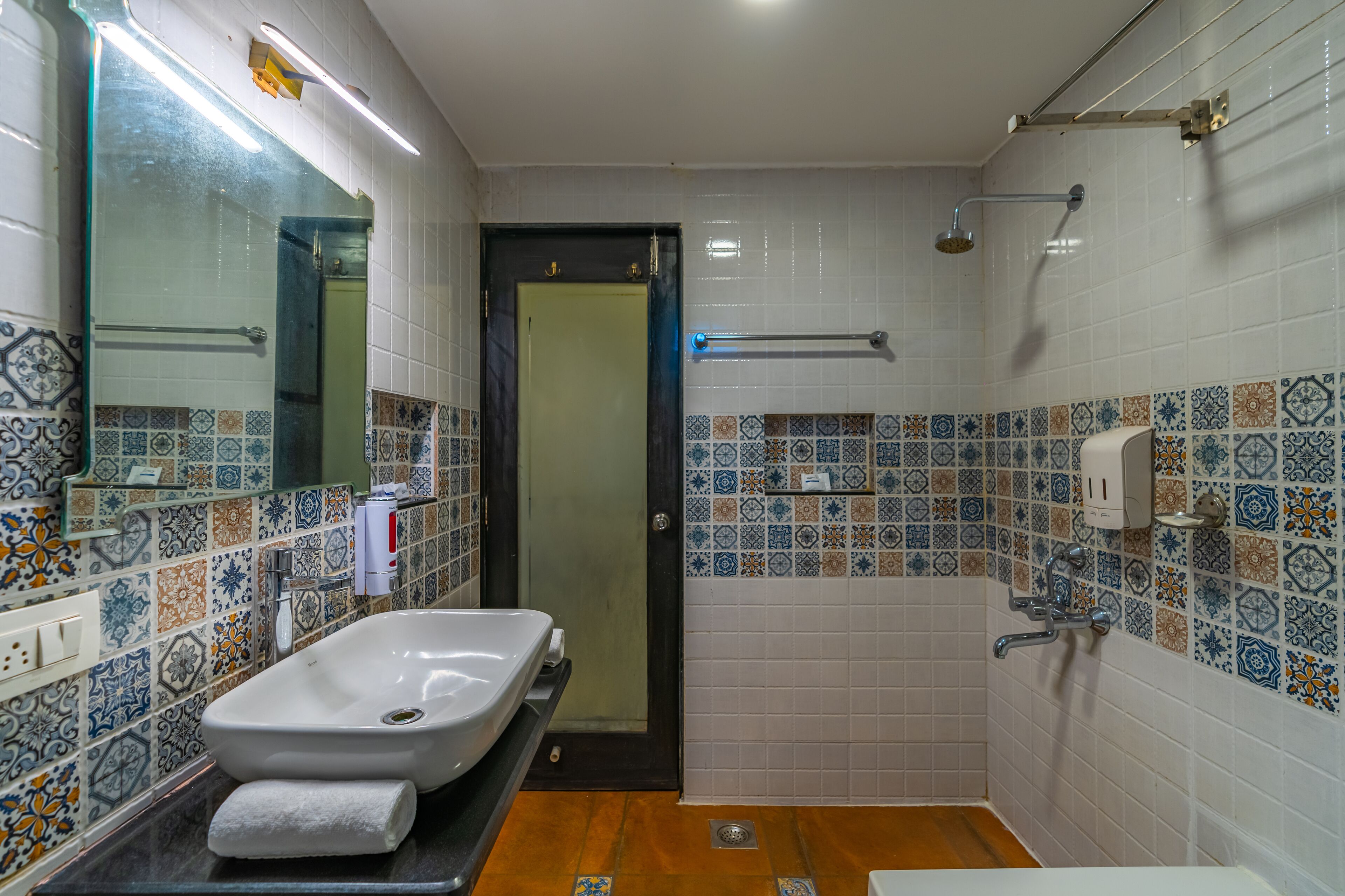 A bathroom with a large sink, a mirror, a shower, and a door.
