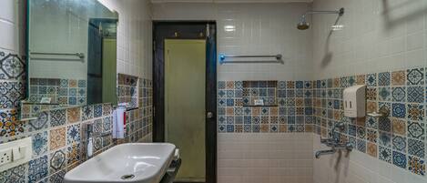 A bathroom with a large sink, a mirror, a shower, and a door.