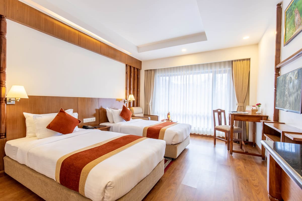 Une chambre d’hôtel avec deux lits, des têtes de lit en bois, un bureau et une chaise.