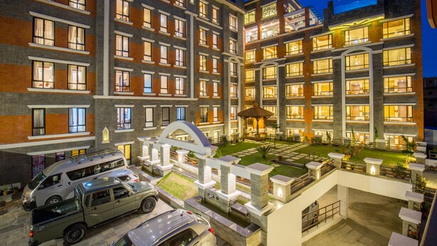 Un hotel de varios pisos con patio, asientos exteriores y una zona cubierta.
