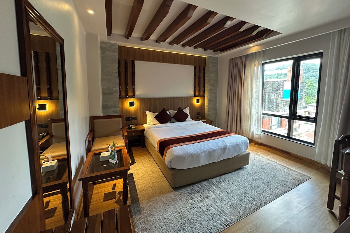 Une chambre d’hôtel moderne dotée d’un grand lit, d’un bureau, d’une chaise et offrant une vue sur la ville grâce à de grandes fenêtres.
