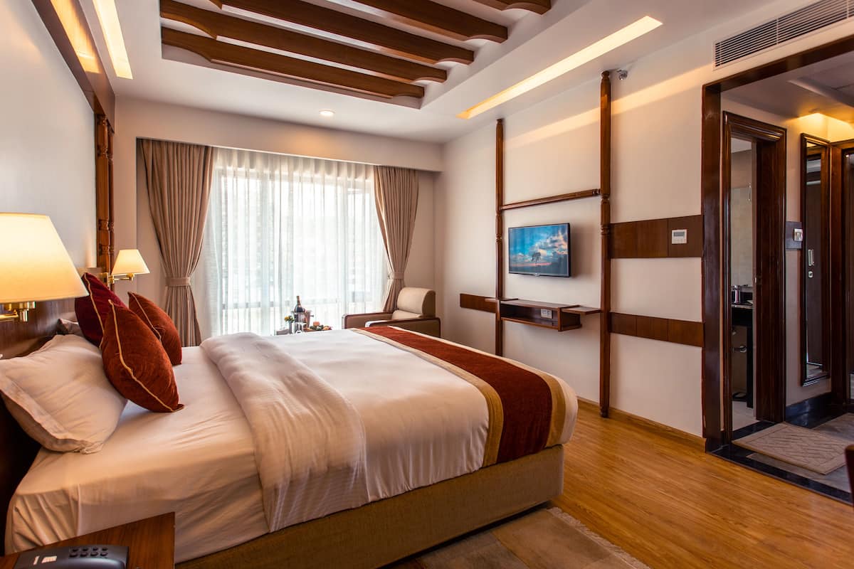 Une chambre d’hôtel avec un grand lit, une télévision, un bureau et une porte donnant sur une salle de bain.