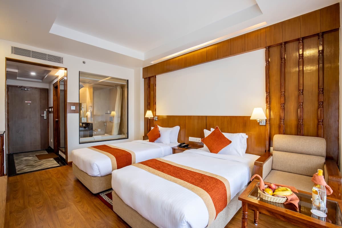Une chambre d’hôtel avec deux lits, un coin salon, un miroir et une tête de lit en bois.