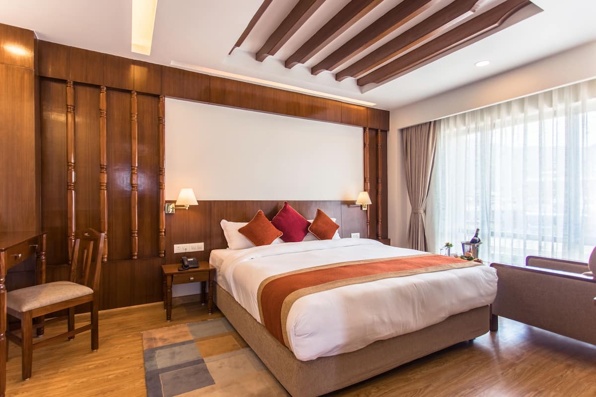 Une chambre d’hôtel avec un grand lit, des boiseries, un bureau et une chaise.