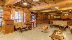 Un interior de madera con una mesa de recepción, sofás, mesas y una maceta decorativa.