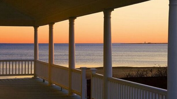 A wooden deck with white railings overlooking a calm sea at sunset. - Lotus Provincetown (Provincetown)