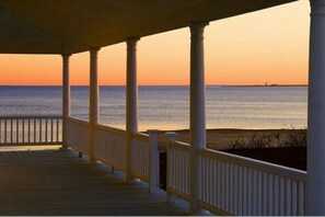 A wooden deck with white railings overlooking a calm sea at sunset. - Lotus Provincetown (Provincetown)
