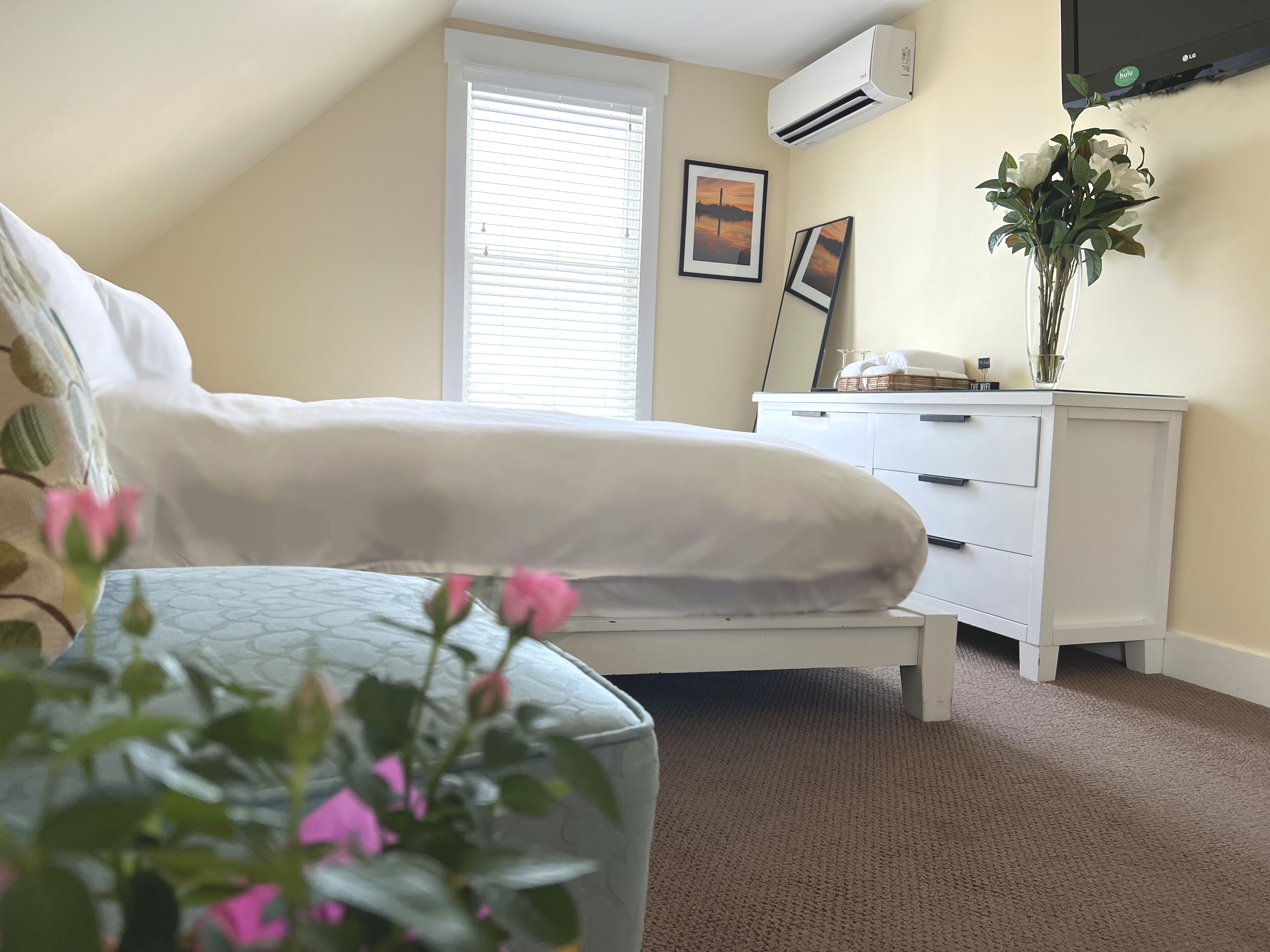 A bedroom with a bed, a nightstand, a dresser, and a window with blinds.