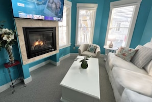 A living room with a fireplace, a flat-screen TV mounted above it, and a sofa.