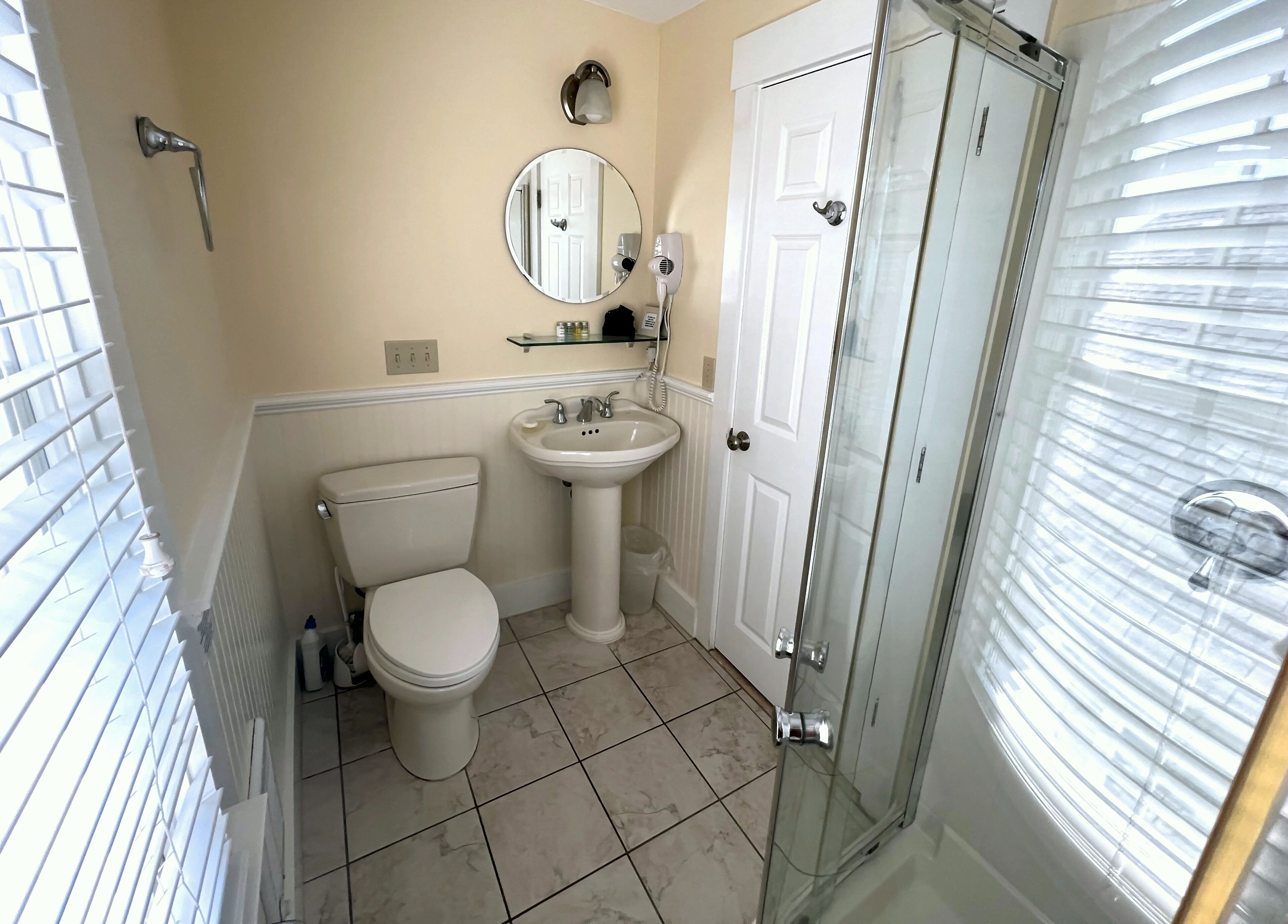 A bathroom with a toilet, sink, and glass shower enclosure.