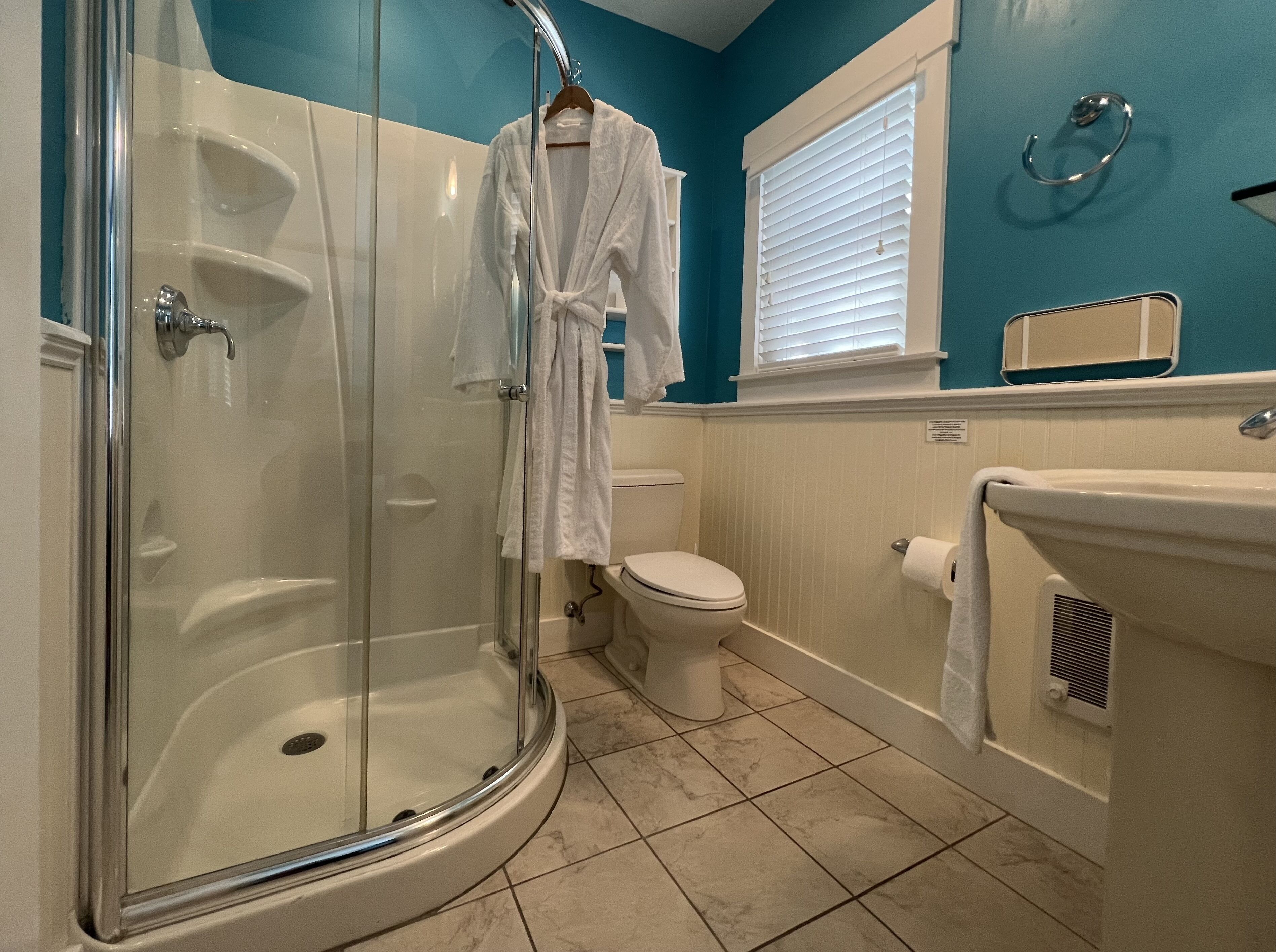 A bathroom with a glass-enclosed shower, a toilet, and a sink.