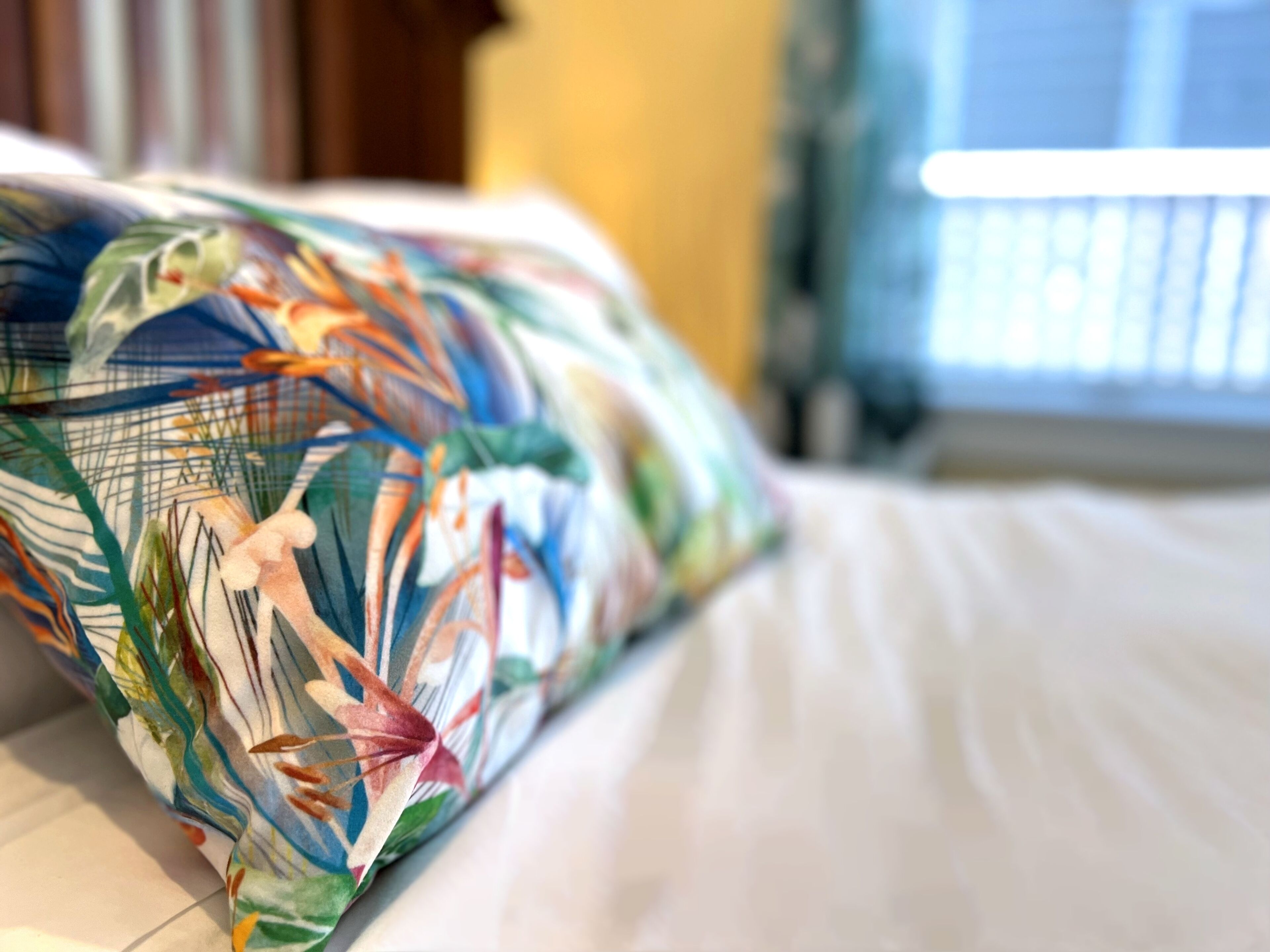 Una cama con un cojín estampado con motivos florales.