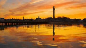 A sunset over a body of water with a prominent tower in the distance.