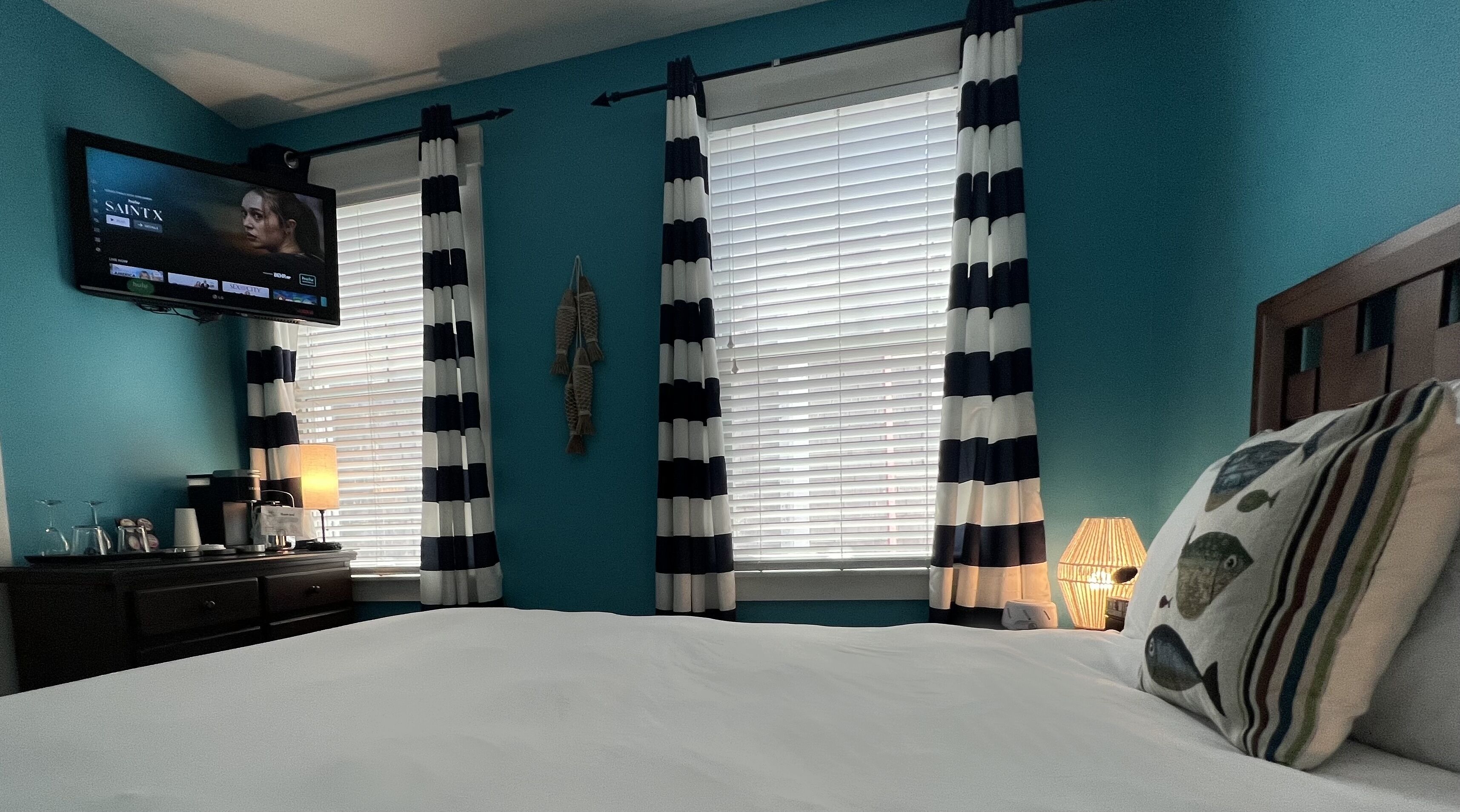 A bedroom with a bed, a TV mounted on the wall, and curtains.