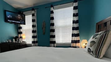 A bedroom with a bed, a TV mounted on the wall, and curtains.