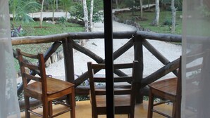 Conjunto de mesa e cadeira de madeira montado numa varanda com vista para uma área arborizada.