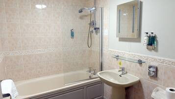 A bathroom with a bathtub, a sink, a glass shower enclosure, and a mirror.