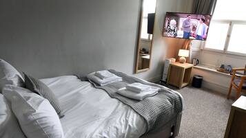 Een hotelkamer met een bed, een televisie, een bureau en een stoel.
