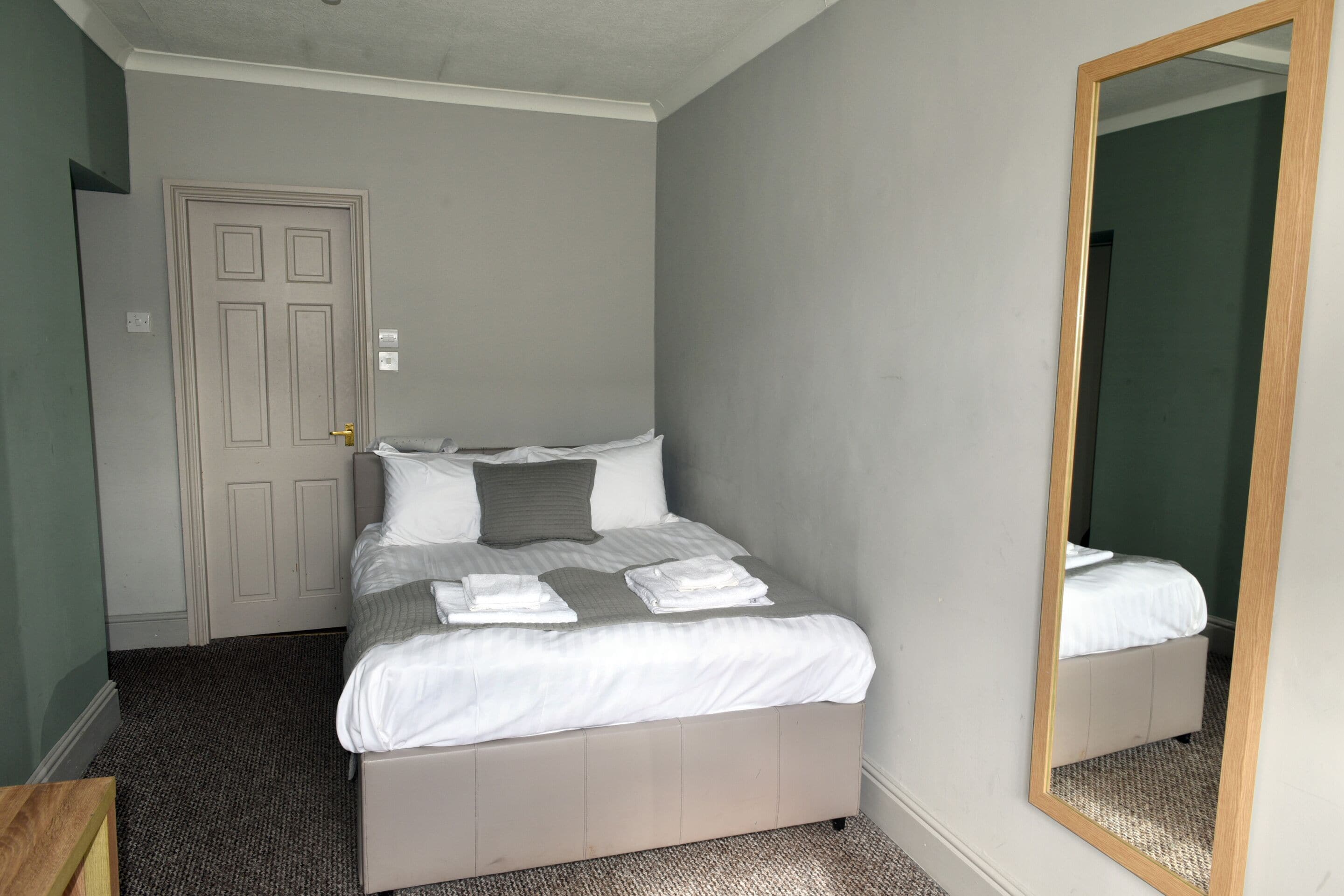 Una habitación de hotel con cama, espejo y puerta.