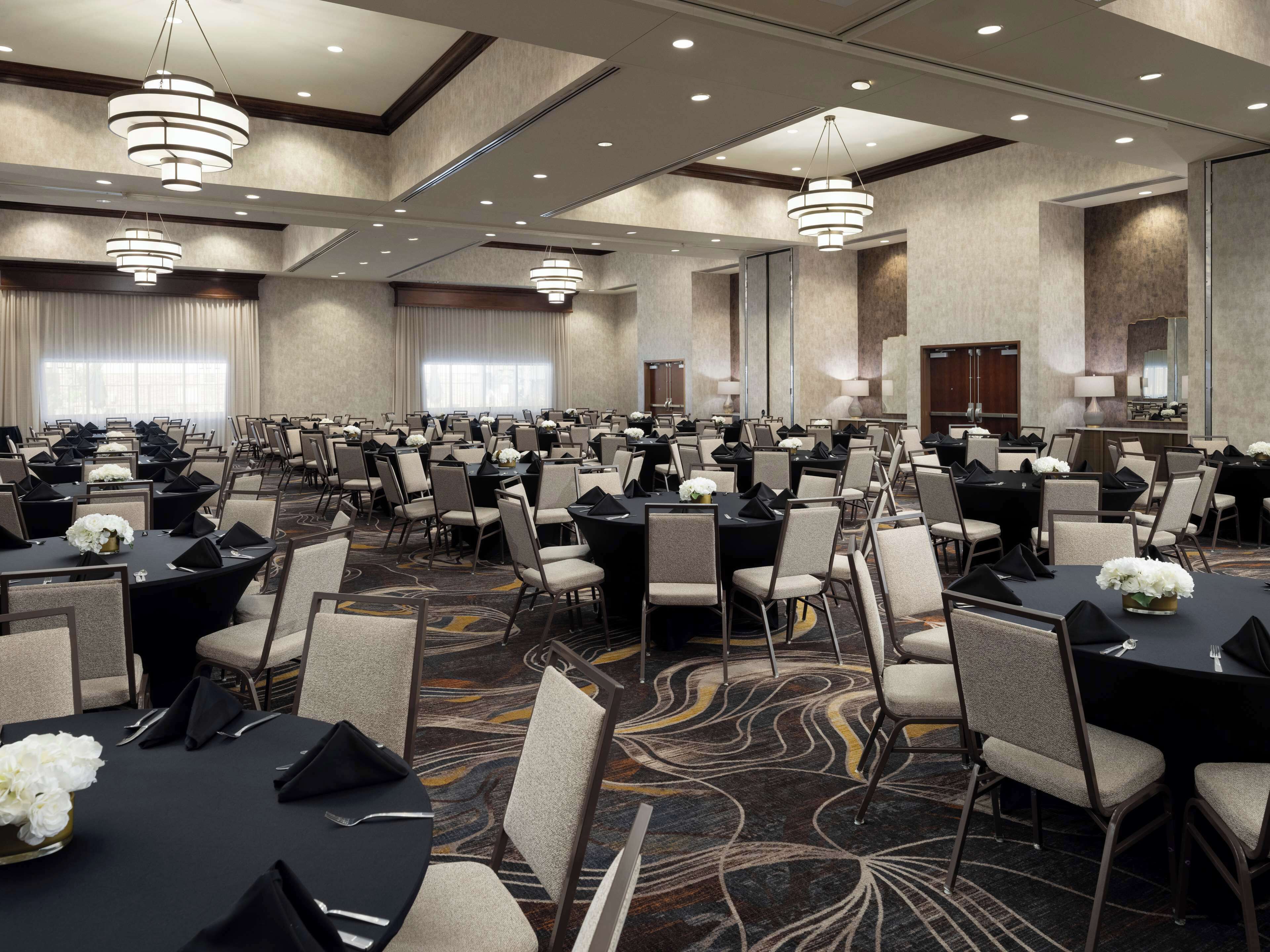 A large, well-lit conference room with multiple tables and chairs, arranged for a formal event.