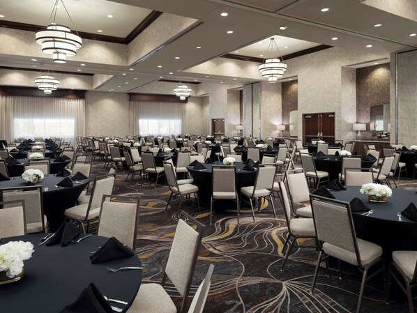 A large, well-lit conference room with multiple tables and chairs, arranged for a formal event.