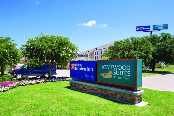 Placa para Hilton Garden Inn e Homewood Suites by Hilton, com uma carrinha azul estacionada por perto.