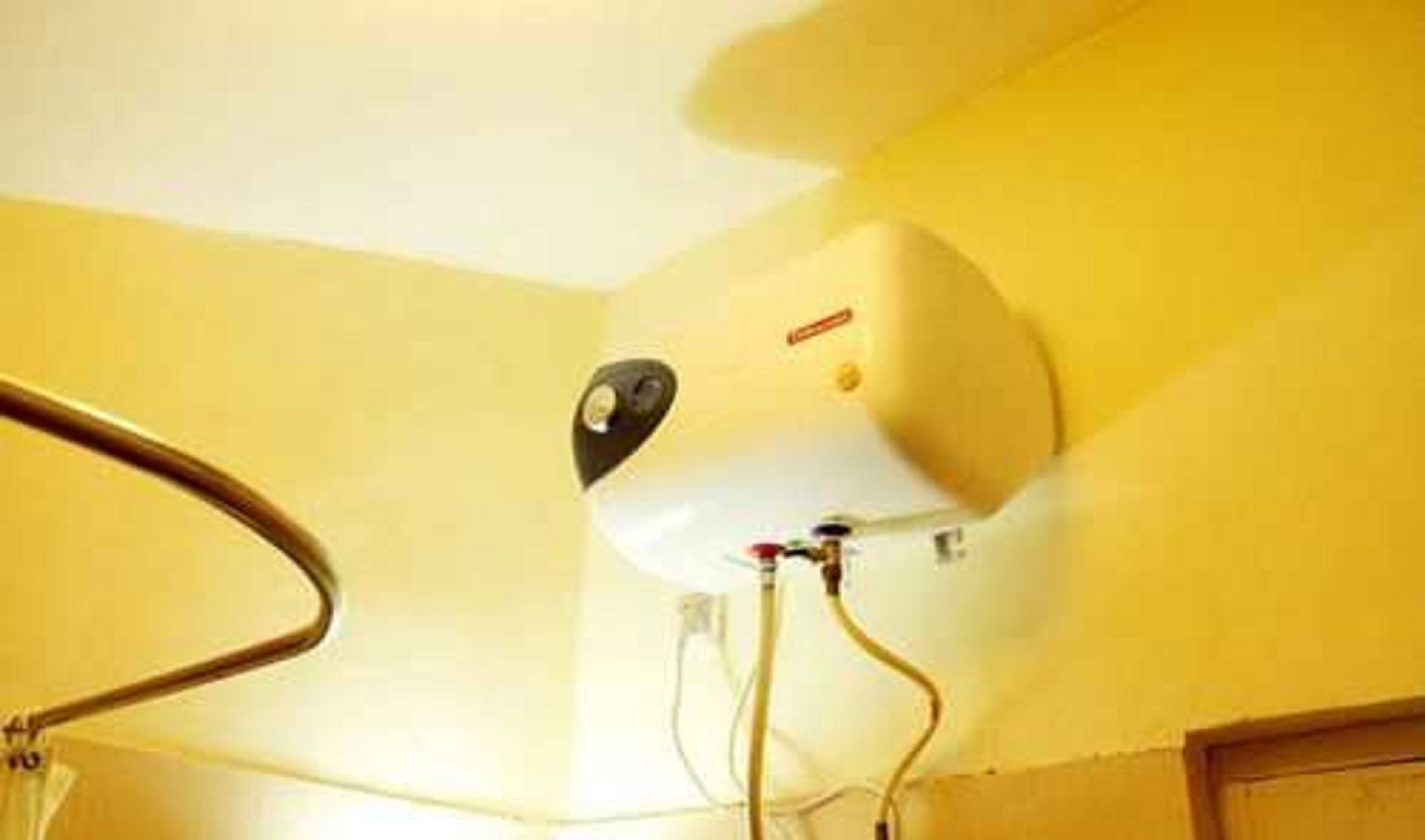 Calentador de agua instalado en una pared, con tuberías y panel de control visibles.