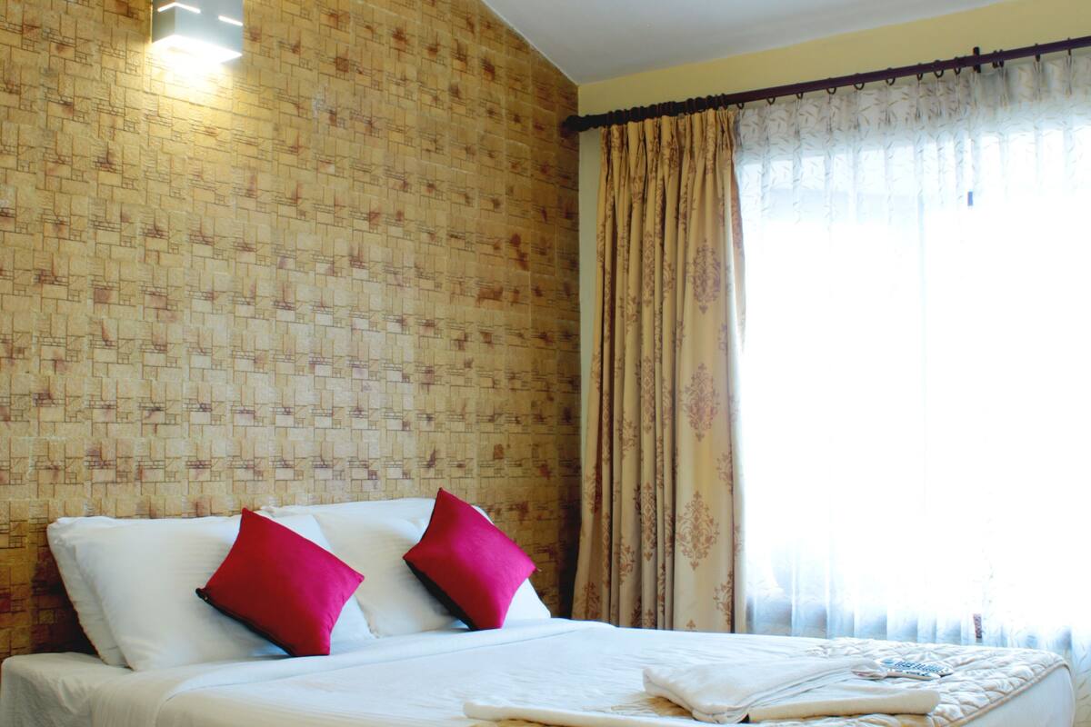 Ein Hotelzimmer mit einem großen Bett, einem Deckenventilator und einem Fenster mit Vorhängen.