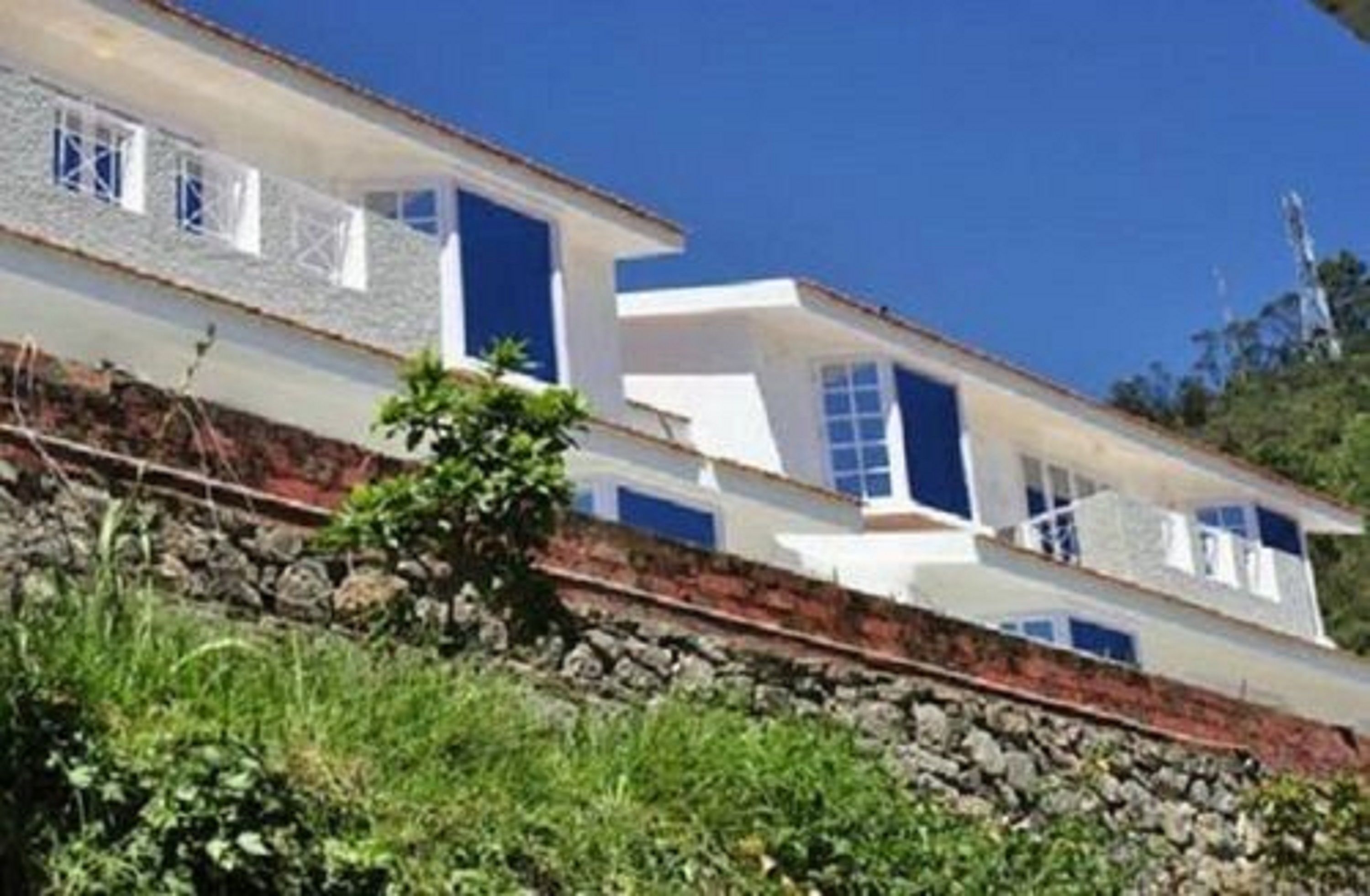 Una casa moderna de dos pisos con base de piedra, paredes blancas y detalles azules.