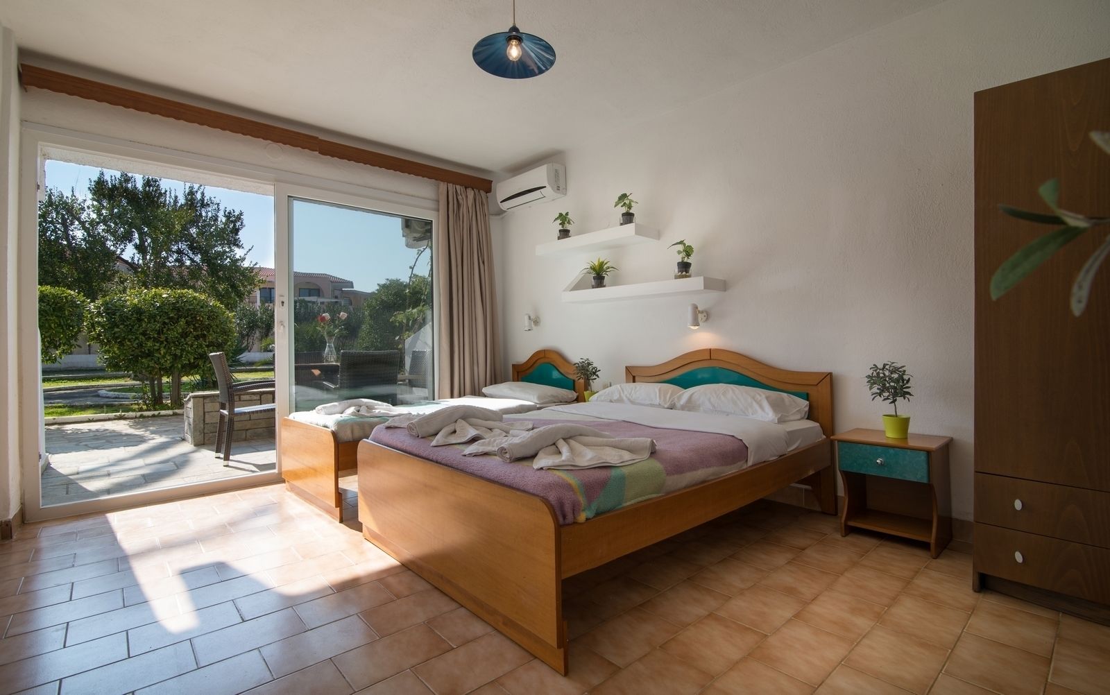 Un dormitorio con una cama grande, una mesita de noche, un armario y vistas al exterior.