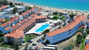 An aerial view of a coastal hotel with a swimming pool, beach access, and multiple buildings with red-tiled roofs. - Toroni Blue Sea Hotel & Spa (Sithonia)