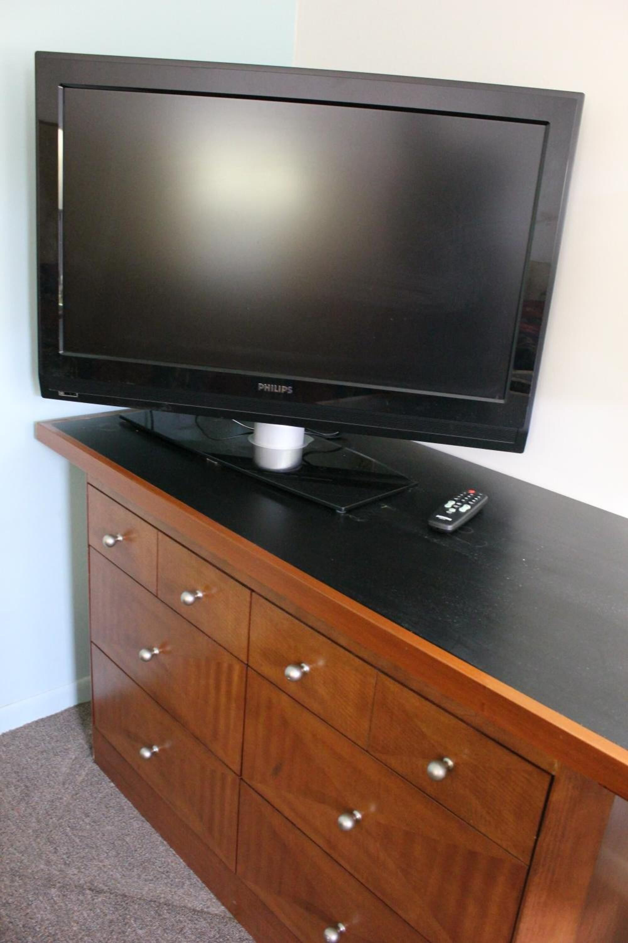 A flat-screen TV on a wooden cabinet with drawers.