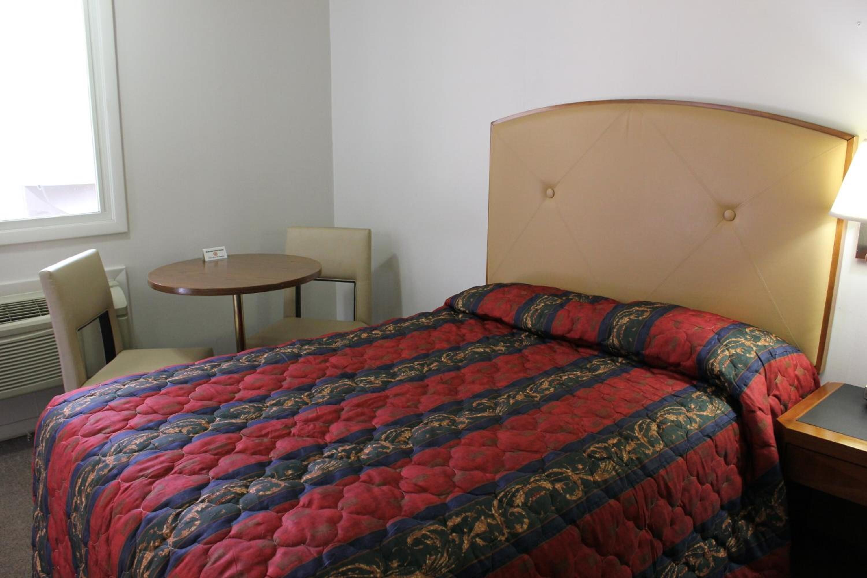 A hotel room with a bed, a round table, and two chairs.