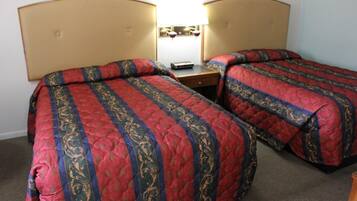 A hotel room with two single beds, each with a headboard, a bedside table, and a lamp.