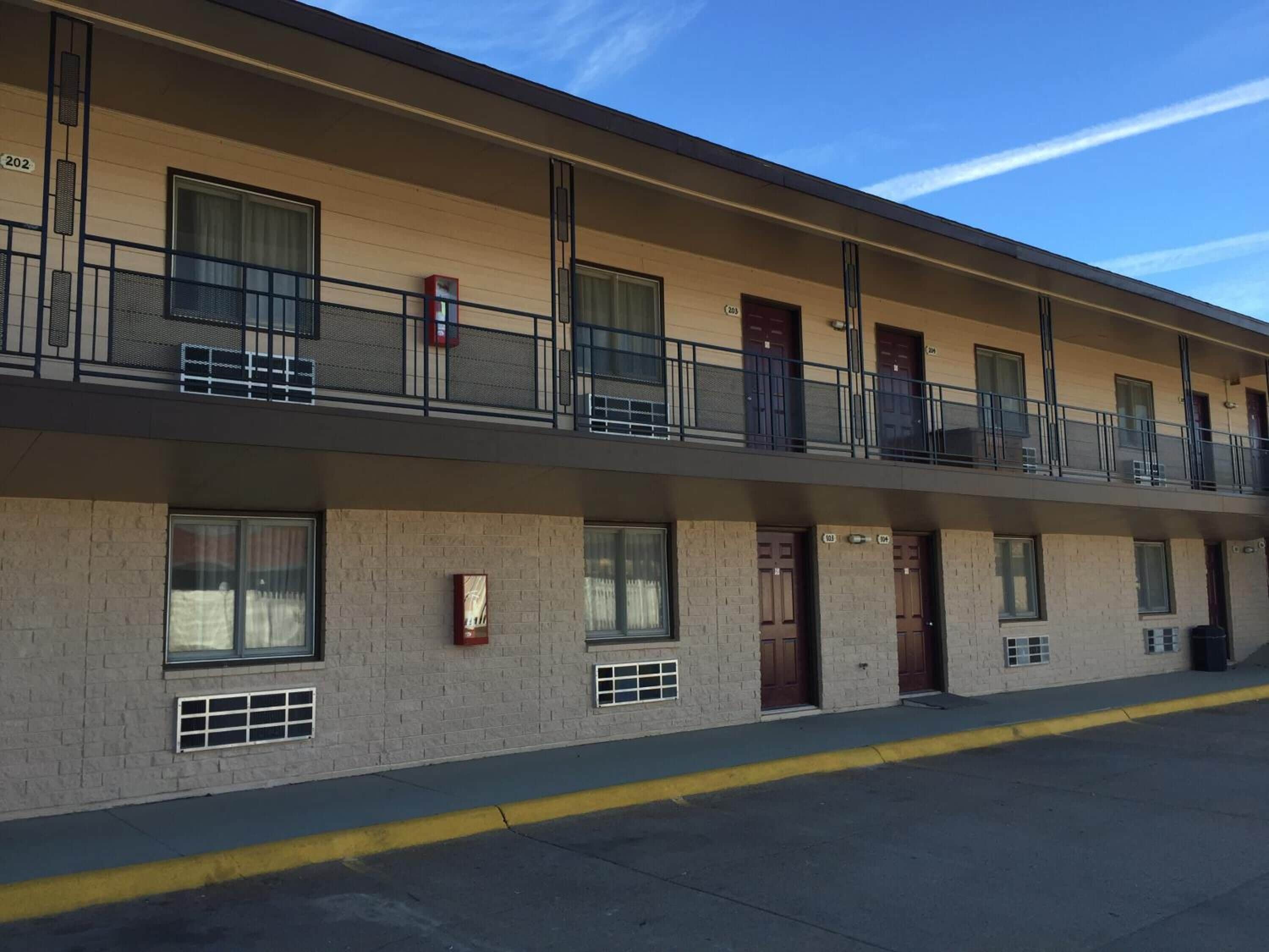 A multi-story motel with a flat facade, balconies, and a clear sky.