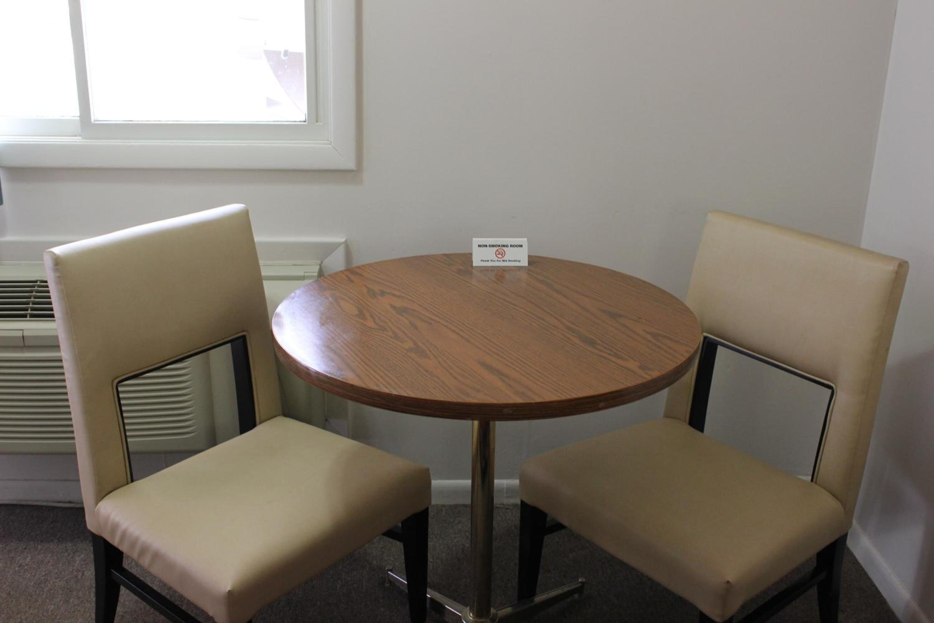 Habitación para no fumadores con una mesa de madera redonda y dos sillas color beige.