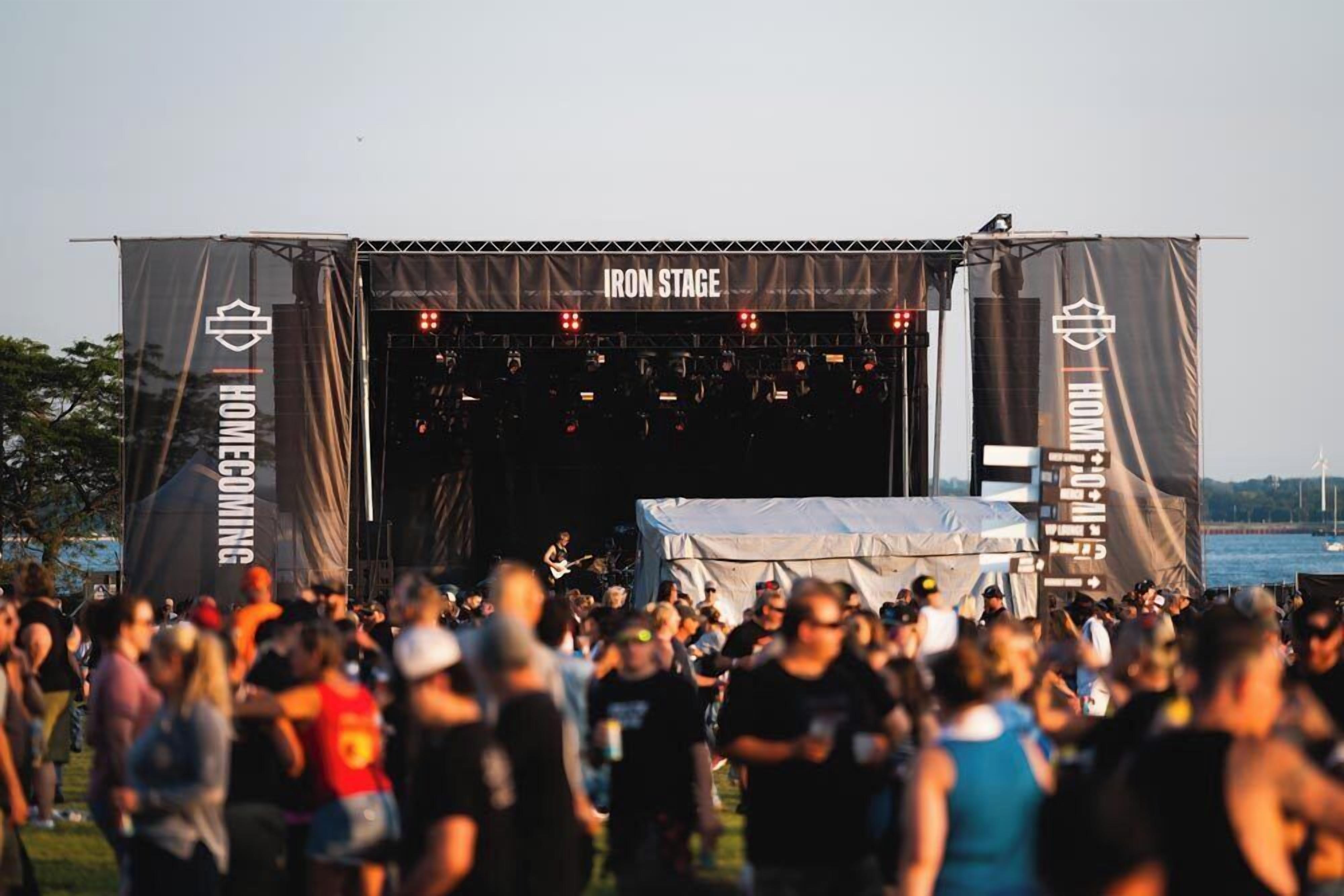 Un escenario con un cartel que dice 'IRON STAGE' y 'HOMECOMING' a cada lado, rodeado de gente.