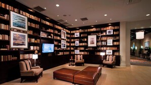 Una biblioteca con estanterías, un televisor y zonas de estar.