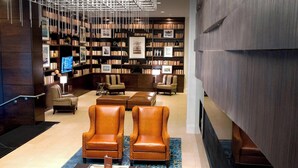 Una biblioteca con estanterías, sillones de cuero y un candelabro.
